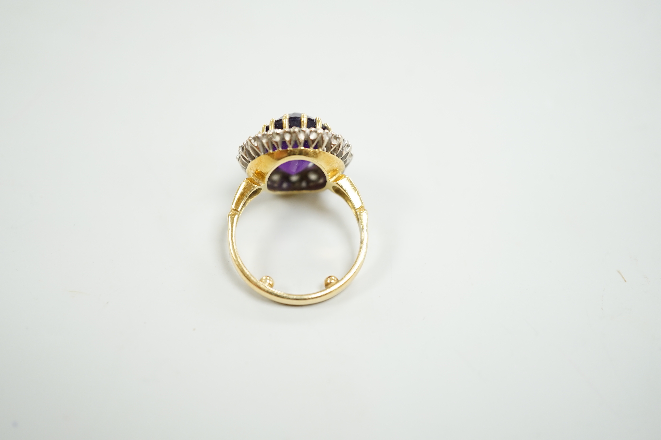 A yellow metal, amethyst and diamond set oval cluster dress ring, size K, gross weight 7.5 grams.